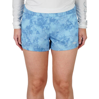 Close-up view of a person wearing blue patterned shorts.